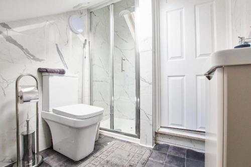 レッドブリッジにあるSleek Gem of London -2 Bedroom Apartment with Parkingのトイレとシャワー付きの白いバスルーム