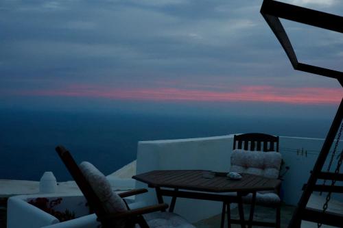 Ein Tisch und Stühle auf einem Balkon mit Blick auf den Sonnenuntergang in der Unterkunft Anerada sunset in Áno Meriá