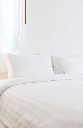 a white bed with white sheets and a window at Örebro City Hostel in Örebro