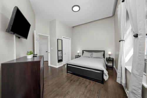 a bedroom with a bed and a flat screen tv at Cozy 1 Bedroom Apt near Logan Sq in Chicago