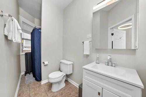 a white bathroom with a toilet and a sink at Cozy 1 Bedroom Apt near Logan Sq in Chicago