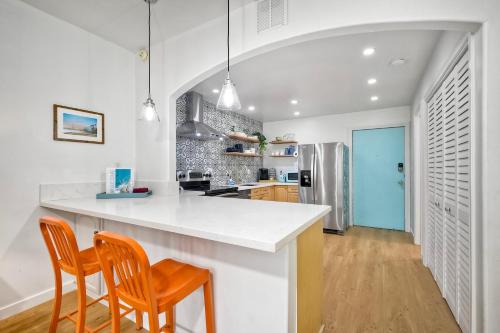 a kitchen with a white counter and two chairs at La Costa Escape - Pool, BBQ, Gated Parking in Encinitas