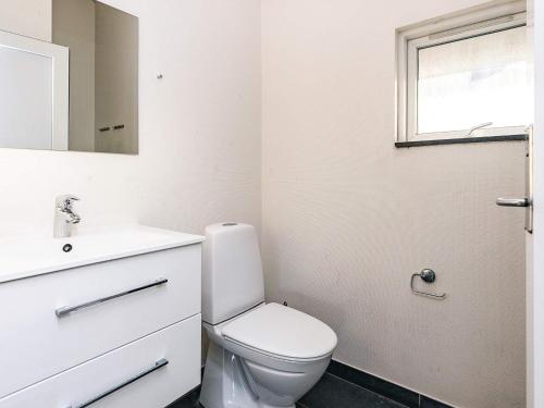 a bathroom with a toilet and a sink and a window at 4 star holiday home in Idestrup in Marielyst