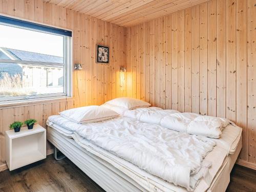 a bedroom with a large bed in a wooden wall at 4 star holiday home in Idestrup in Marielyst