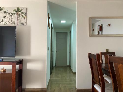 a hallway with white walls and a television and chairs at BUIN CENTRO Departamento in Maipo