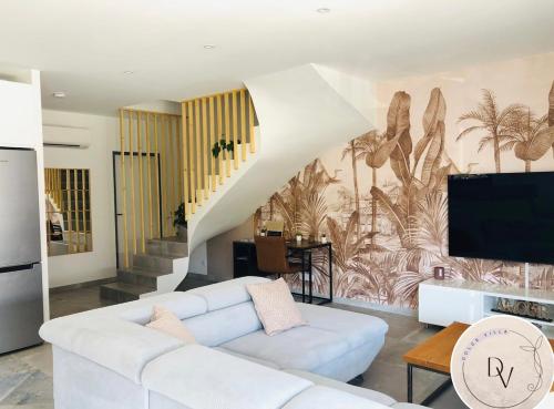 ein Wohnzimmer mit einem weißen Sofa und einem Fernseher in der Unterkunft La Dolce Villa - Bali&les Cévennes in Alès