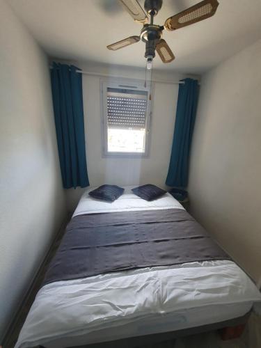 - une chambre avec un lit, un ventilateur de plafond et une fenêtre dans l'établissement Joli appartement cosy T2, à Leucate-Plage