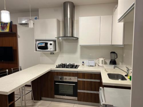 a kitchen with white cabinets and a stove top oven at Apartamento de Lujo en el Canal Isuto ZONA EQUIPETROL in Santa Cruz de la Sierra