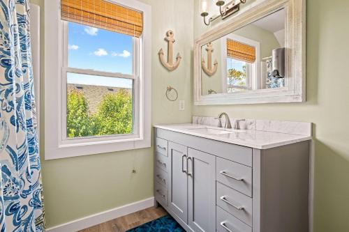 un bagno con un lavandino, uno specchio e una finestra di Aminas Cottage 3 Bedroom Home a Kill Devil Hills