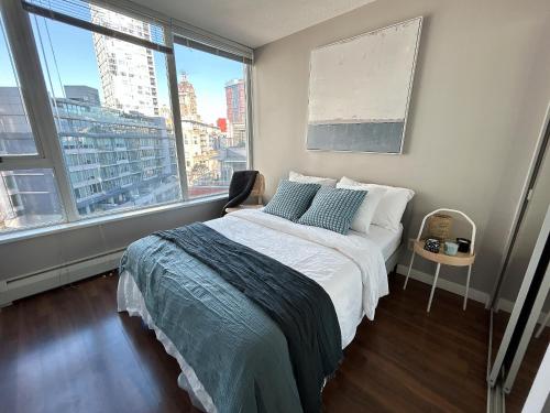 a bedroom with a bed and a large window at Modern spacious Apt plus Solarium and Den in Downtown Vancouver with Parking and Pool in Vancouver