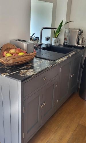 a kitchen counter with a bowl of fruit and a sink at Hall Farm Barns in Monk Fryston