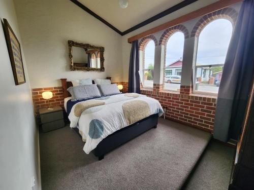 a bedroom with a bed and a brick wall at The Church House- Boutique Comfort in Balclutha
