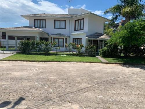 a white house with a driveway in front of it at Casa em praia de Garopaba 48- in Garopaba