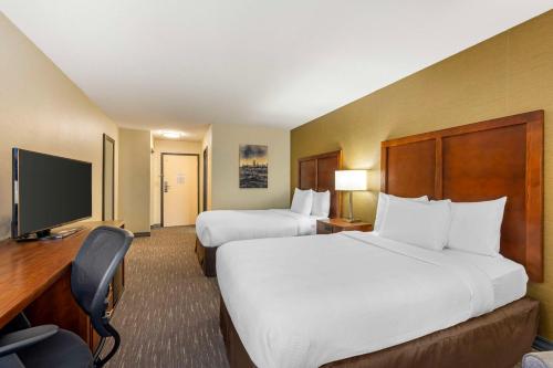 a hotel room with two beds and a flat screen tv at Best Western Chicago - Downers Grove in Downers Grove