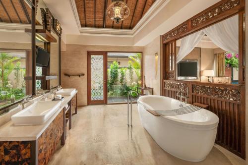 a bathroom with two sinks and a tub and a television at The St. Regis Bali Resort in Nusa Dua