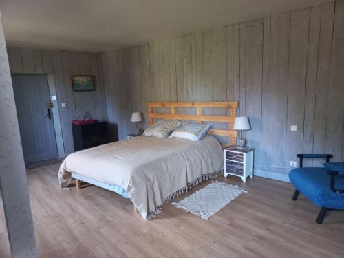 a bedroom with a large bed and a blue chair at La Grange Aux Mille Feuilles in Castres