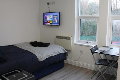 a bedroom with a bed and a desk and a tv on the wall at Bevois Valley Serviced Apartments - Comfort and Convenience in Southampton