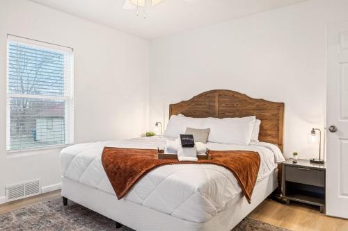 a white bedroom with a large bed with a wooden headboard at Renovated House for 14 in Wentzville MO in Wentzville