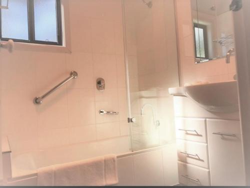 a white bathroom with a shower and a sink at Edgewater Terraces at Metung in Metung