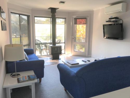 a living room with a blue couch and a fire place at Edgewater Terraces at Metung in Metung
