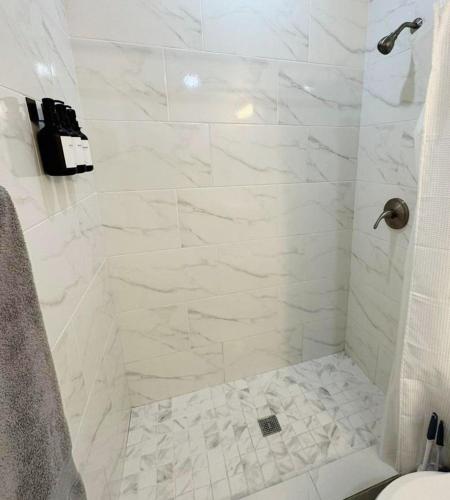 a bathroom with a shower with white marble tiles at Private studio by Miami International Airport in Miami