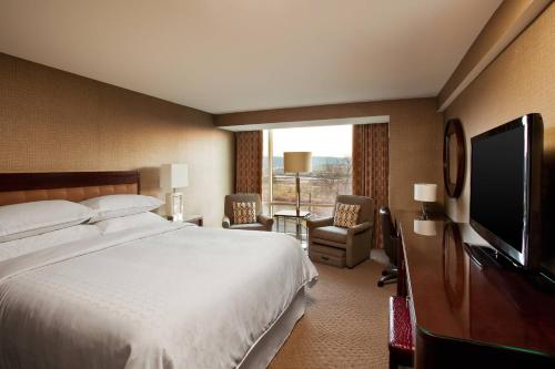 a hotel room with a bed and a flat screen tv at Sheraton Valley Forge King of Prussia in King of Prussia
