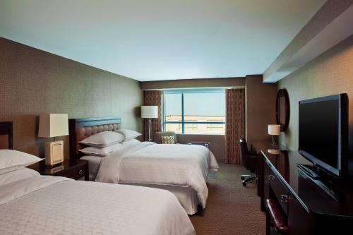 a hotel room with two beds and a flat screen tv at Sheraton Valley Forge King of Prussia in King of Prussia