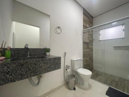 a bathroom with a toilet and a sink and a mirror at Pousada Paraíso das Águas Capitólio in Capitólio