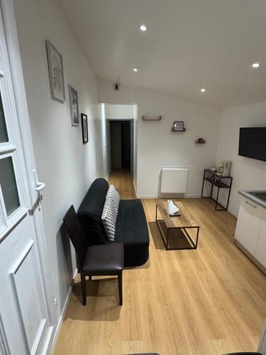 a living room with a black couch and a table at Appartement RDC vu sur jardin in La Roche-sur-Yon