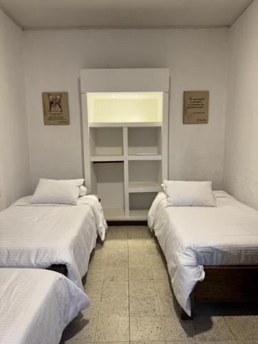 Dos camas en una habitación con sábanas blancas. en Vivienda turística Casa Rionegro colonial, en Rionegro