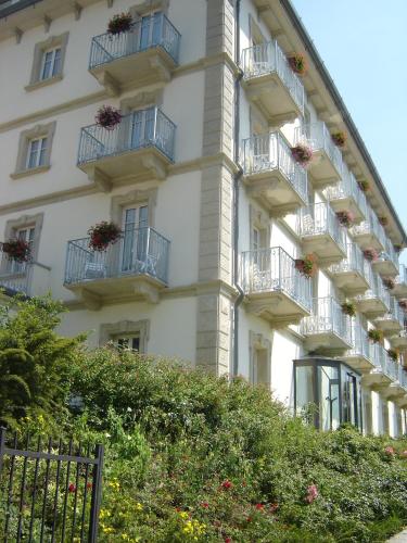 a white building with balconies and flower boxes on it at Hotel Lario in Mezzegra