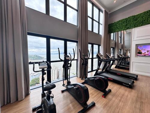 a gym with treadmills and ellipticals in a room with windows at Sauna Academia Sinuca 3 min a Pé mar Ar quente in Itapema