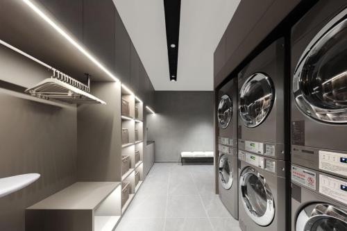 a laundry room with three washer and dryer machines at Atour Light Hotel Xiamen Convention and Exhibition Center Software Park Phase II in Xiamen