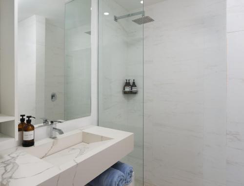 a white bathroom with a sink and a shower at Coralita Apartments in Saint Michael
