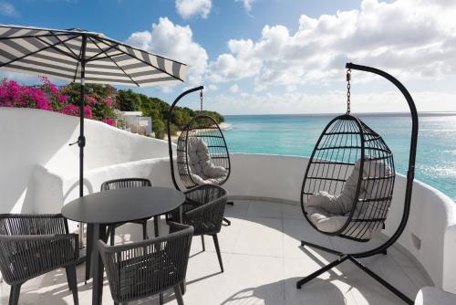 a patio with a table and chairs and the ocean at Coralita Apartments in Saint Michael