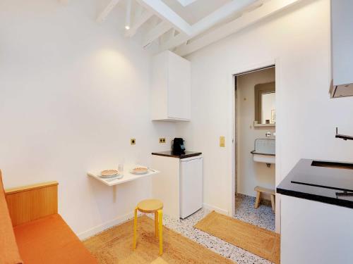 - une cuisine avec des murs blancs et un tabouret dans la chambre dans l'établissement Cosy apartment 2P close to Sacré-Coeur, à Paris