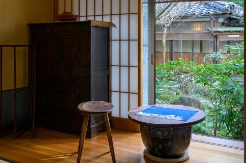 a table and a stool in a room with a window at 岩井温泉　岩井屋 in Iwamicho