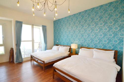 a bedroom with two beds and a blue wall at 蔚藍白鷺民宿 in Donggang