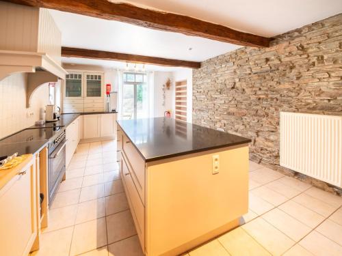 a kitchen with a large island in a room with a stone wall at Historic Watermill in Bohan in Vresse-sur-Semois