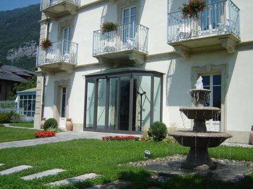 a white house with a fountain in front of it at Hotel Lario in Mezzegra