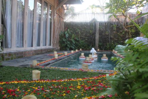 a garden with a pond in a yard with flowers at Umaya Ubud Villa in Ubud