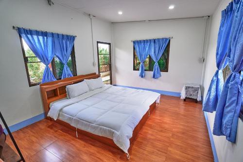 a bedroom with a large bed with blue curtains at Cha-Cha Garden Chiang Mai - บ้านสวนชาช่า เชียงใหม่ in Ban Rong Wua (2)