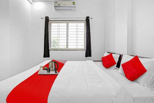 a bedroom with a large white bed with red pillows at Hotel O Yashraj Inn in Nagpur