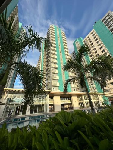 two tall buildings with palm trees in the foreground at Cozy Condo bedroom in Bacolod City in Bacolod