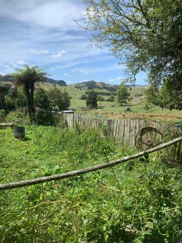 a field with a fence and a field with hills at Avon Cabin by Tiny Away in Huiroa