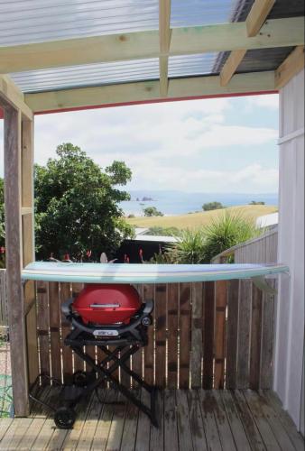 a patio with a red grill on a deck at Studio at Otama Beach in Opito Bay