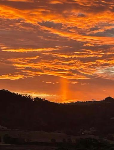 a sunset in the sky over a mountain at Studio at Otama Beach in Opito Bay