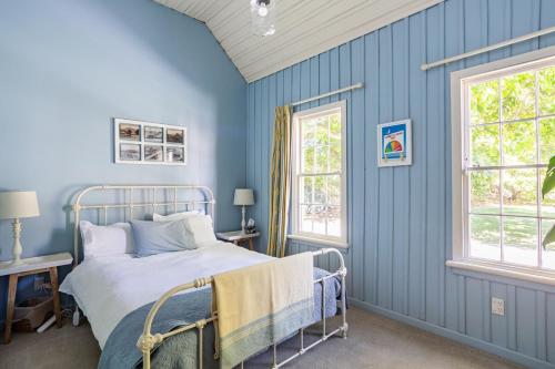 a blue bedroom with a bed and two windows at Old School House in Queenstown