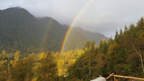 a rainbow over a valley with trees and mountains at Cabaña Ugarit Chabranco Maihue Futrono in Futrono
