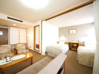 a large hotel room with a bed and a couch at Hotel Il Viale Hachinohe in Hachinohe